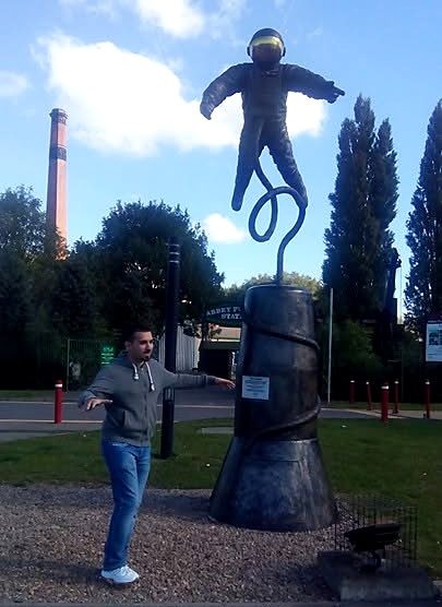Nikos in Leicester, in Pose neben einer Astronautenskulptur.